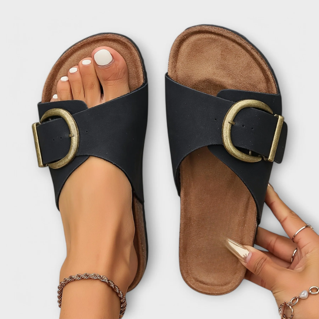 Black flat sandals with wide strap and decorative buckle detail