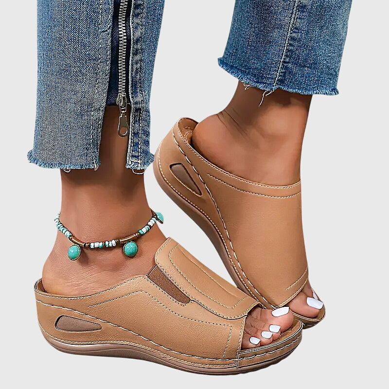 A woman walking confidently in charcoal ergonomic comfort sandals with a broad, cushioned sole.