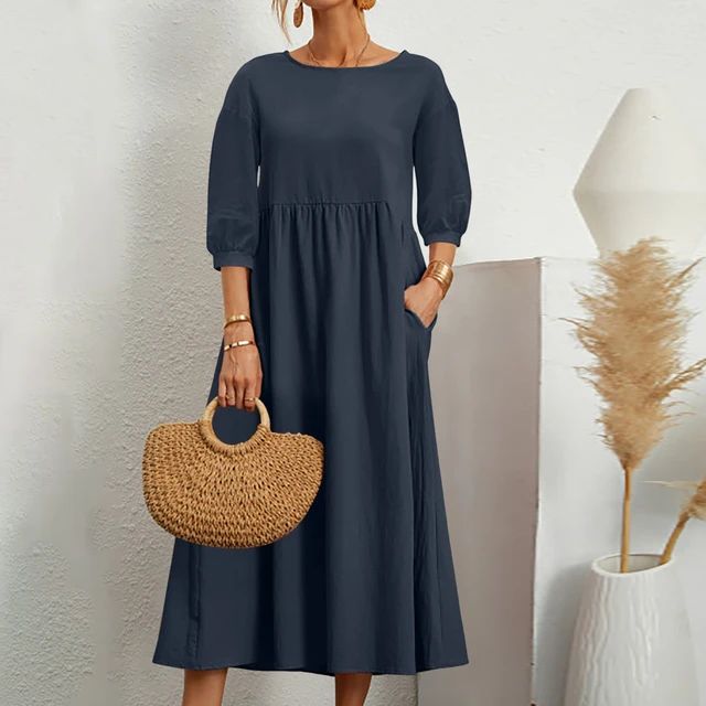 A woman wearing the Sheila fitted waist midi dress with three-quarter sleeves and a flowing skirt.
