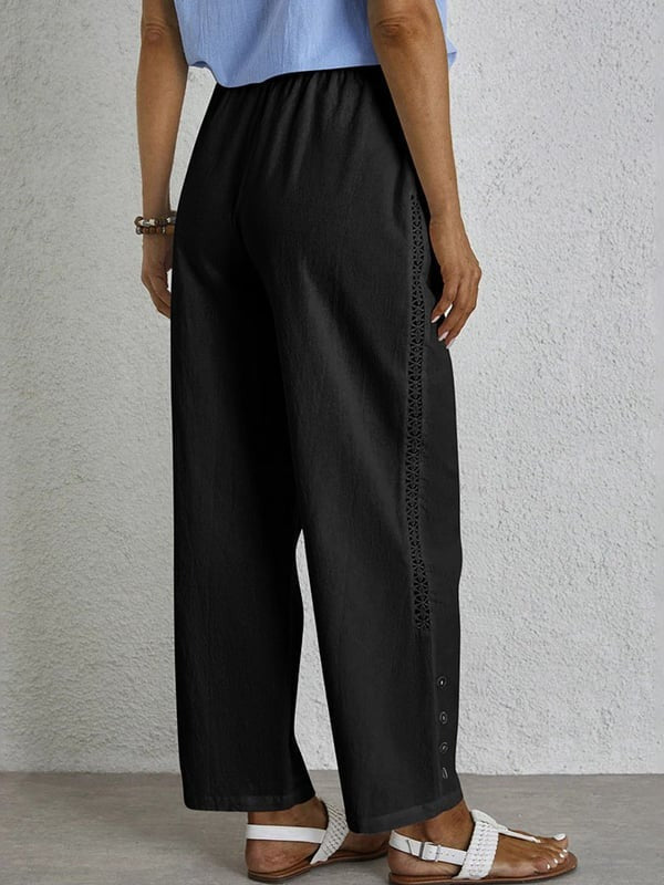 Woman wearing relaxed button-detail trousers with a simple top, out for the day.