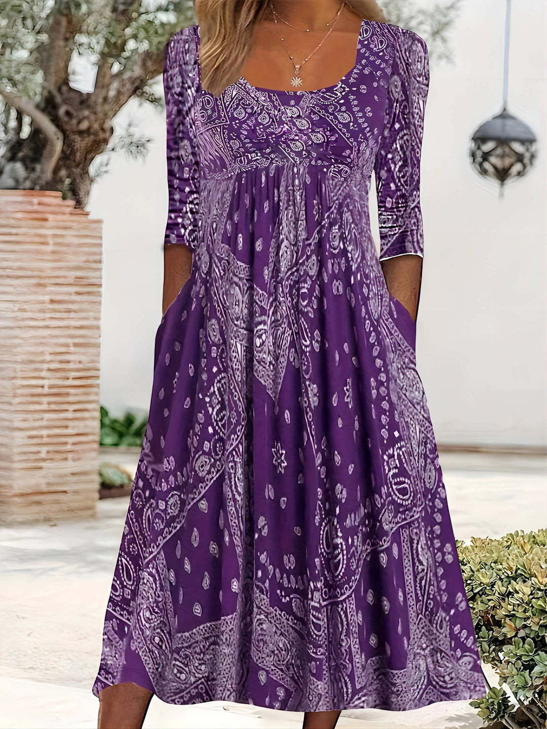 A woman wearing the Maureen long sleeve grey paisley midi dress with a square neckline and flowing skirt, styled for a relaxed day out.