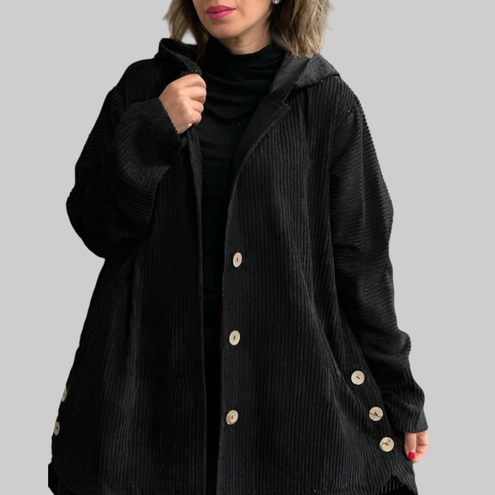A woman wearing a hooded textured jacket outdoors in autumn