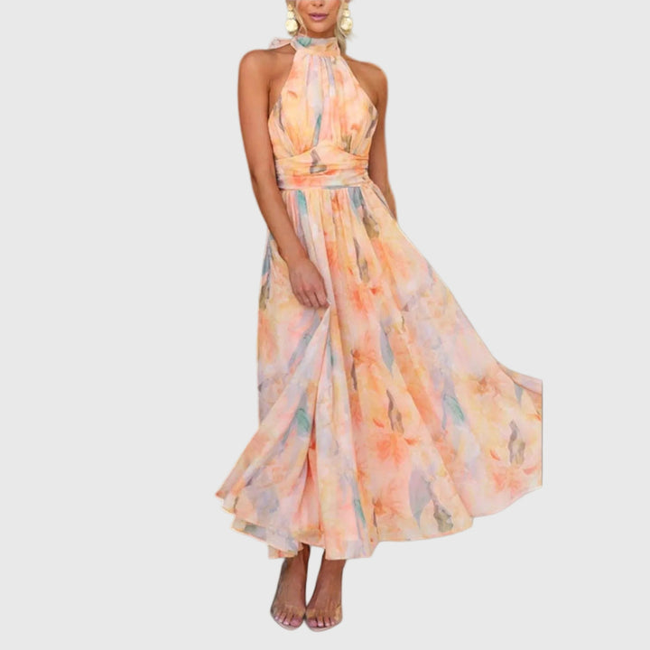Woman wearing the Rachel halterneck maxi dress in warm watercolour tones at an outdoor celebration.