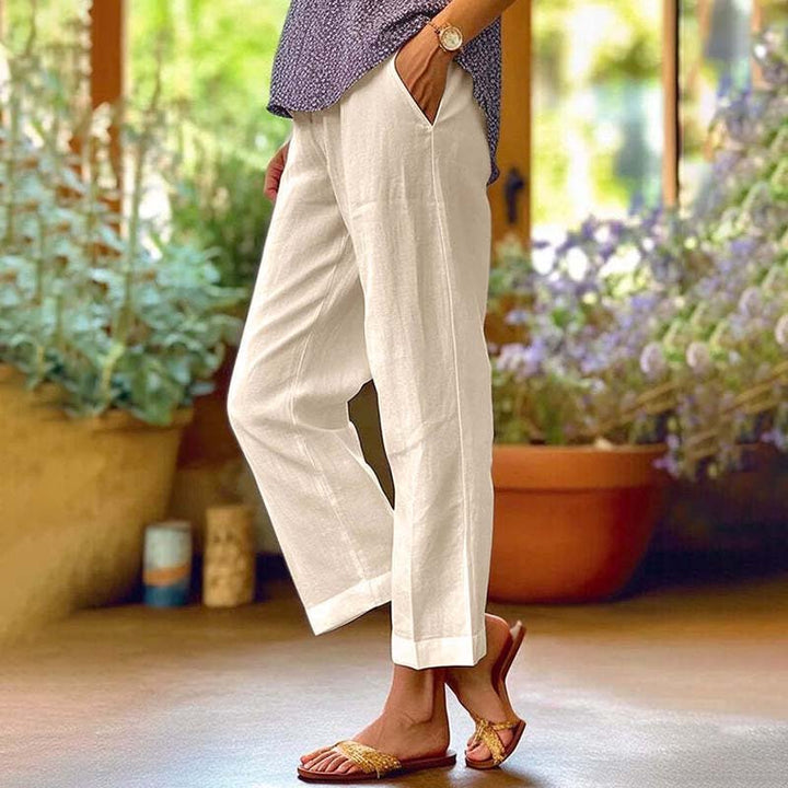 Woman wearing relaxed straight-leg trousers with a soft top, standing in soft daylight.