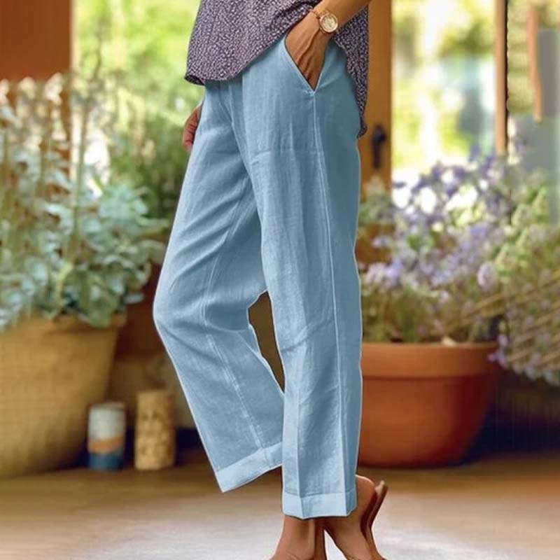 Woman wearing relaxed straight-leg trousers with a soft top, standing in soft daylight.