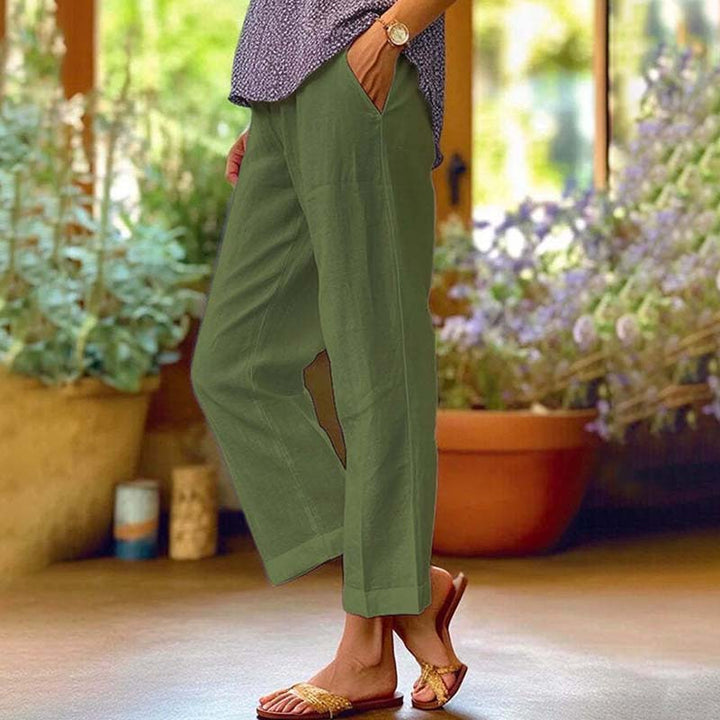Woman wearing relaxed straight-leg trousers with a soft top, standing in soft daylight.