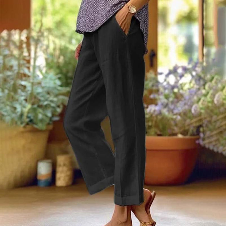 Woman wearing relaxed straight-leg trousers with a soft top, standing in soft daylight.