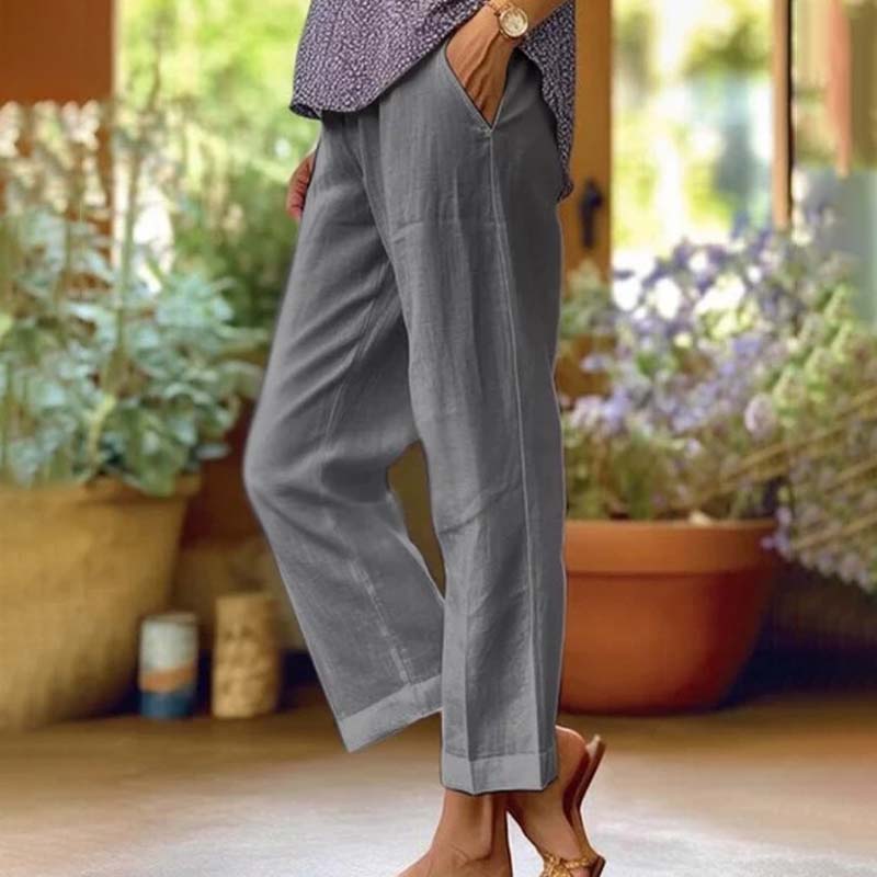 Woman wearing relaxed straight-leg trousers with a soft top, standing in soft daylight.