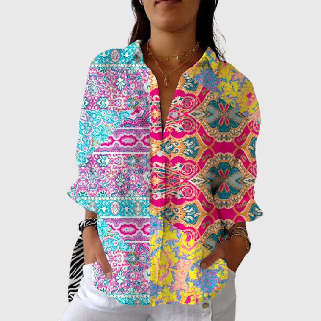 A woman wearing a relaxed colourful printed blouse with adjustable sleeves, styled with trousers for a cheerful day out.