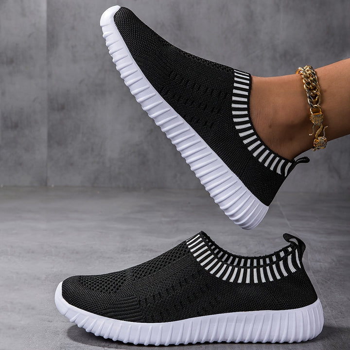 A woman slipping on ultralight sock-style trainers that hug the foot.