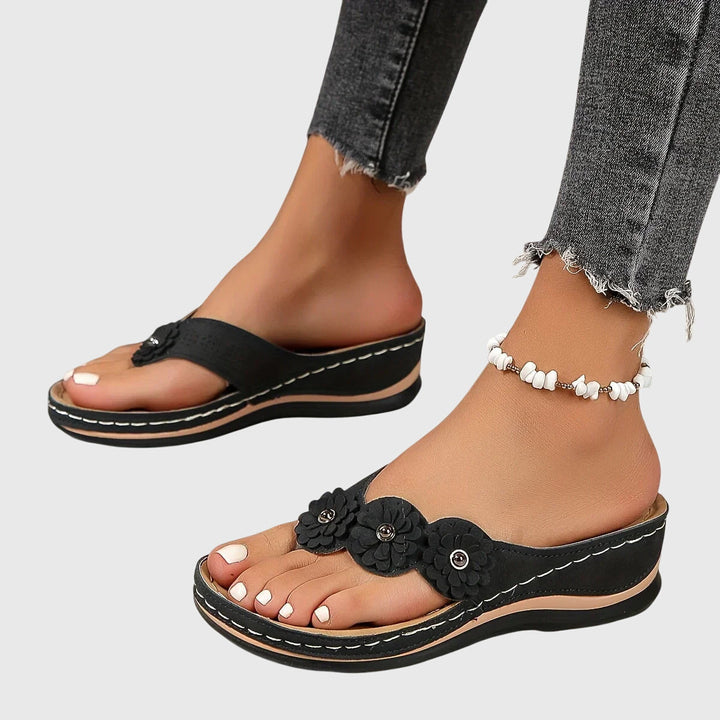 A woman wearing navy cushioned flip-flops with a supportive insole and open-front design.
