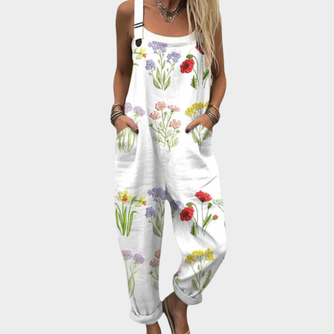 Woman wearing white dungarees printed with a colourful wildflower meadow of poppies and daisies