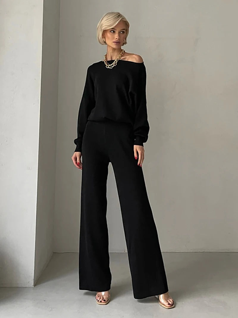A woman wearing an off-shoulder draped top with wide-leg trousers