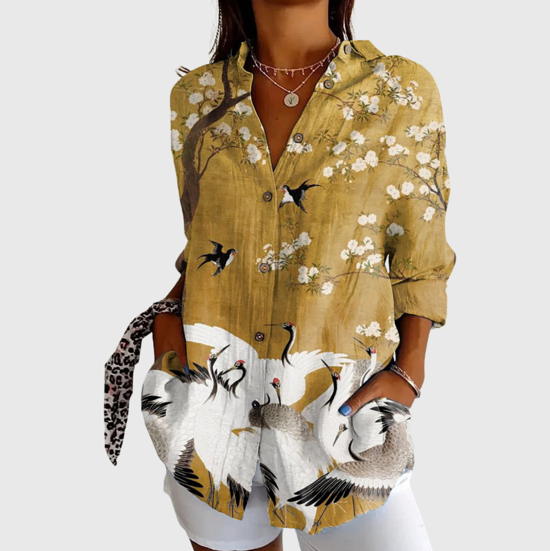 A woman in a colourful floral blouse worn loose, smiling in daylight