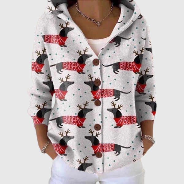 A woman wearing a white hooded button cardigan printed with dachshunds in red jumpers and antlers.