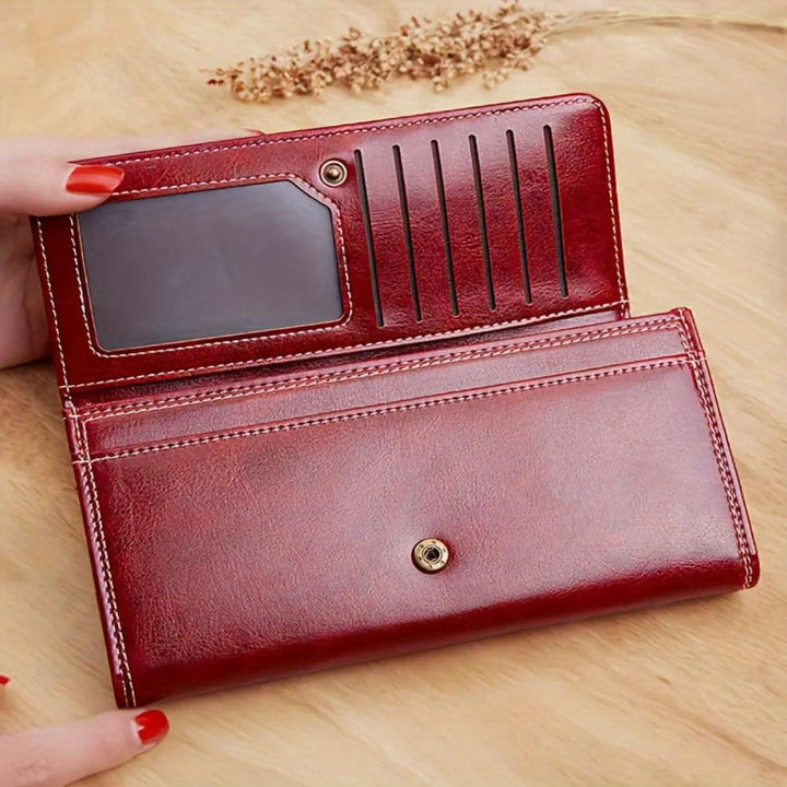 A woman holding an open bifold wallet, tucking a card into its slot.