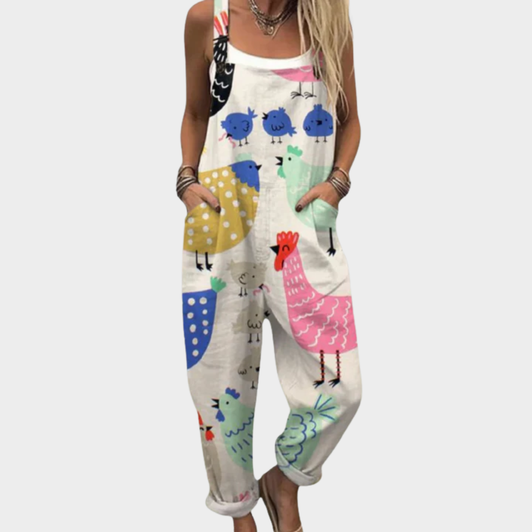 A woman in cream dungarees with a cheerful hen and rooster print, relaxed fit and adjustable straps.