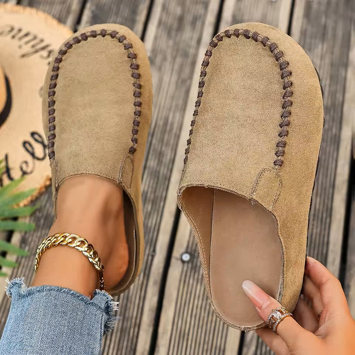 A pair of minimal slip-on loafers in warm brown with a soft footbed and open back