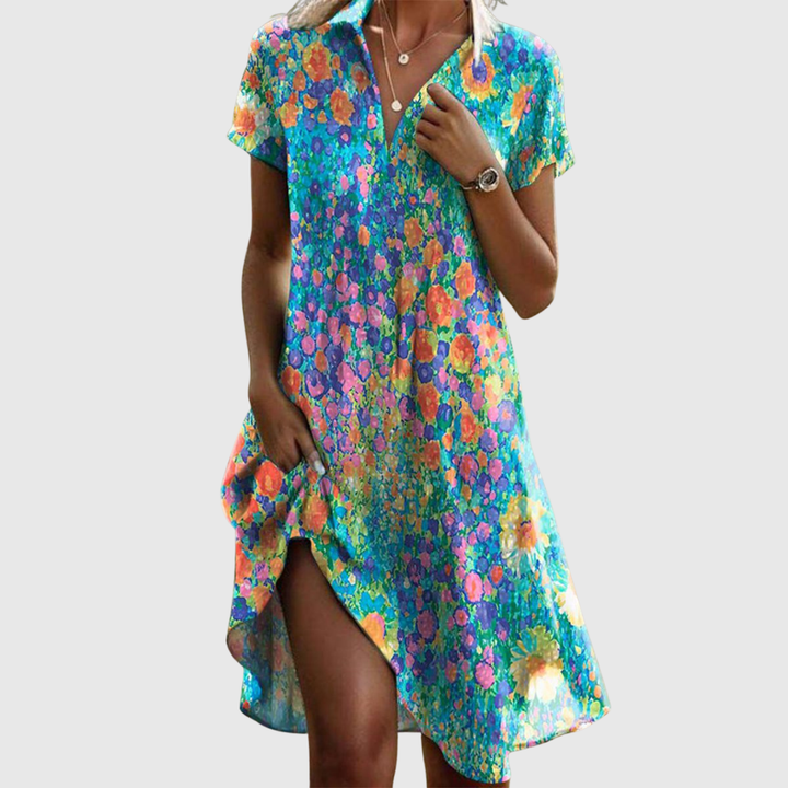 Woman wearing the Amy speckled summer dress in green, smiling in the sunshine outdoors.