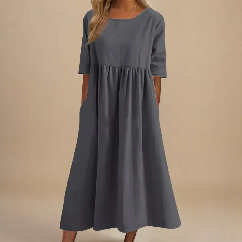 A woman wearing the Carmel flowing day dress with a gathered waist and elbow-length sleeves.