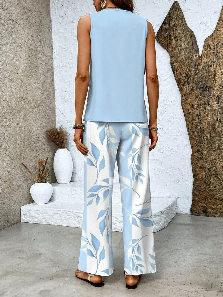 A woman wearing a layered sleeveless top with leaf-print wide-leg trousers, light and elegant.