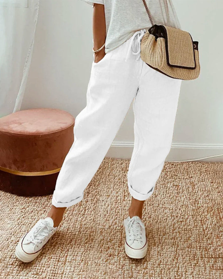 A woman wearing flowing elegant trousers with a soft elastic waist and deep pockets.
