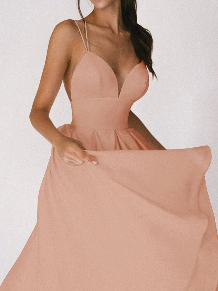 Woman at a summer celebration wearing the Katie minimalist maxi dress with fine double straps and a floating skirt.