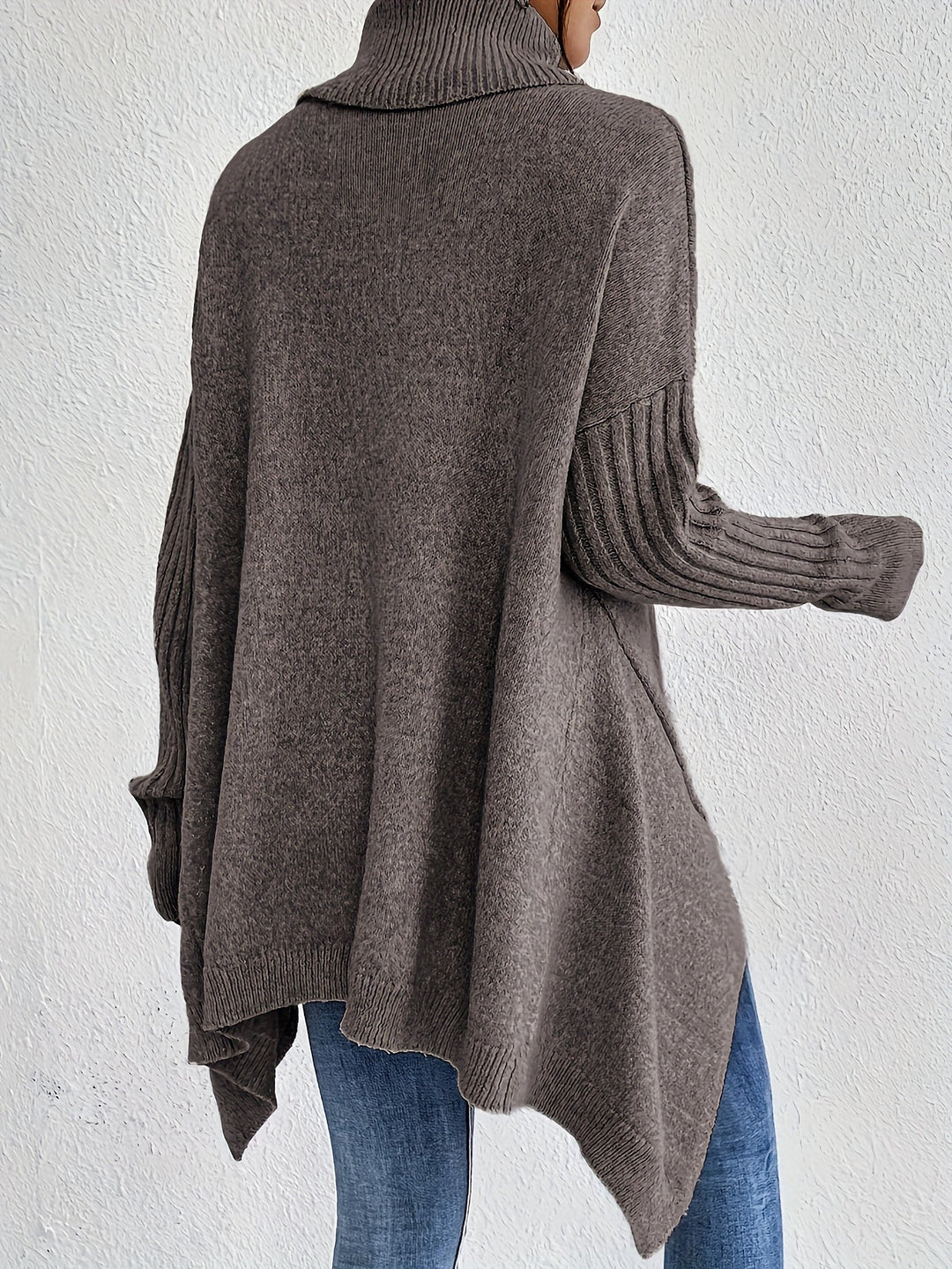 A woman wearing a stand-collar jumper with a chic asymmetric drape, warm and polished.