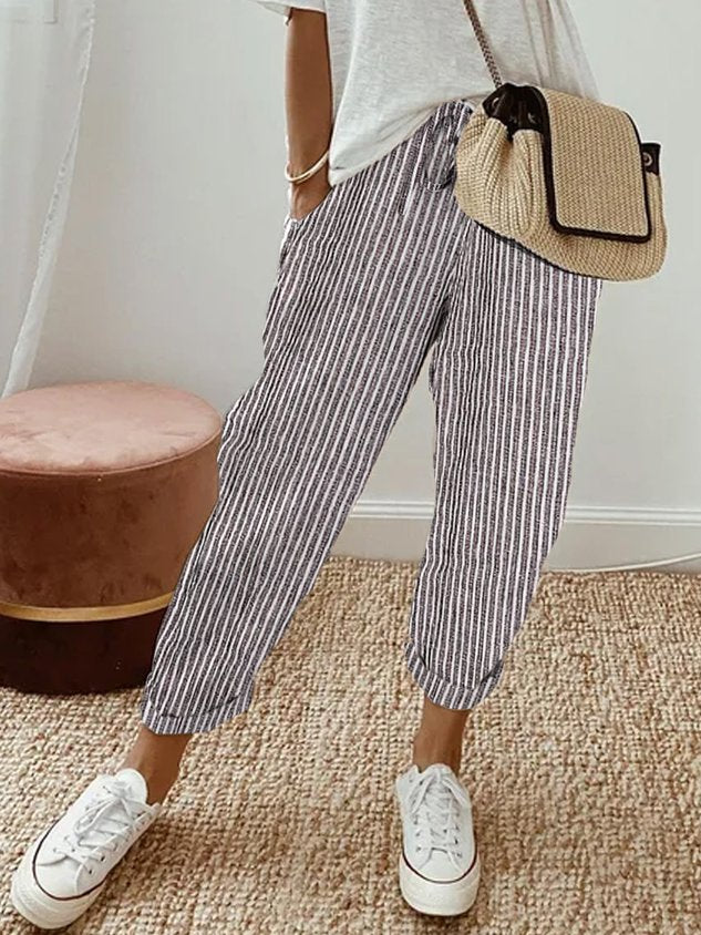 A woman wearing flowing elegant trousers with a soft elastic waist and deep pockets.