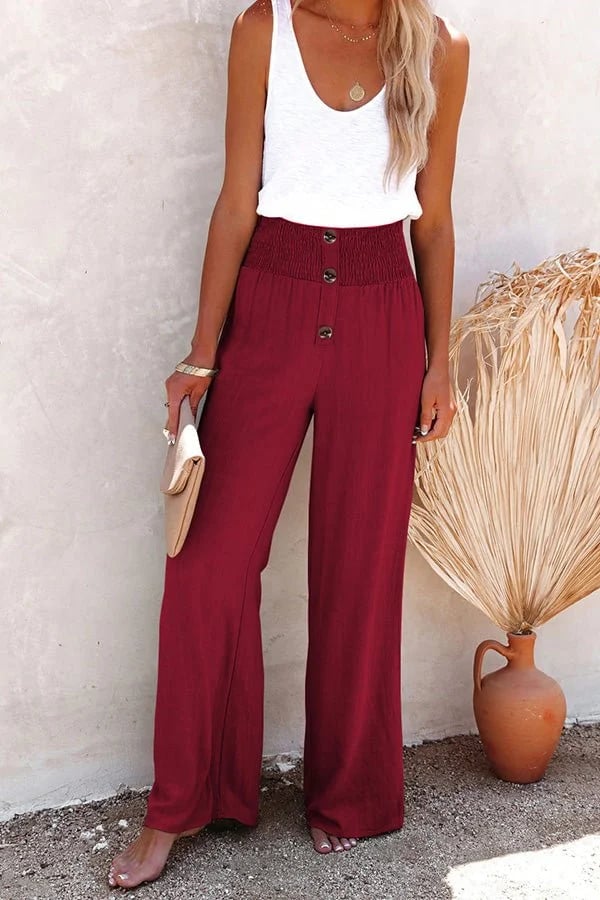 A woman in high-waisted loose wide-leg trousers with subtle button detailing, styled for an elegant everyday look.