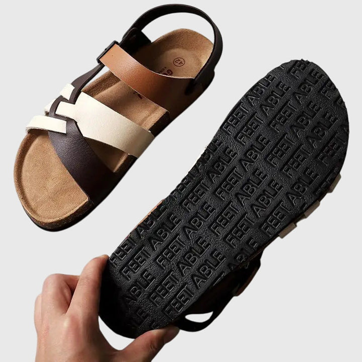 A woman in colourful cross-strap summer sandals with an adjustable ankle buckle on a warm day.
