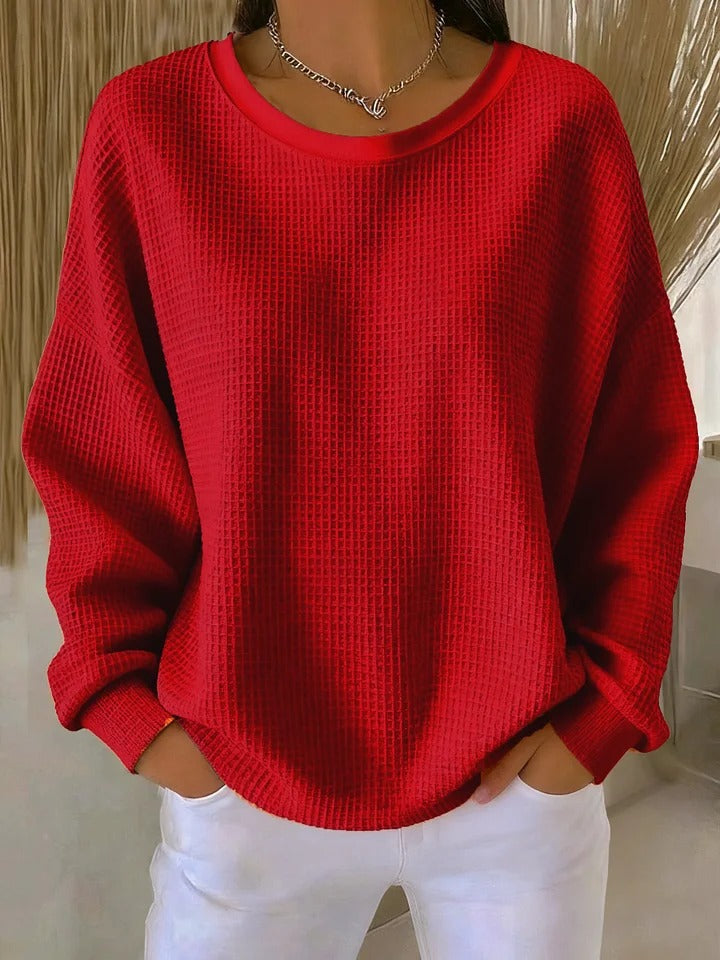 A woman wearing a relaxed-fit waffle-stitch jumper in soft pink with a textured surface
