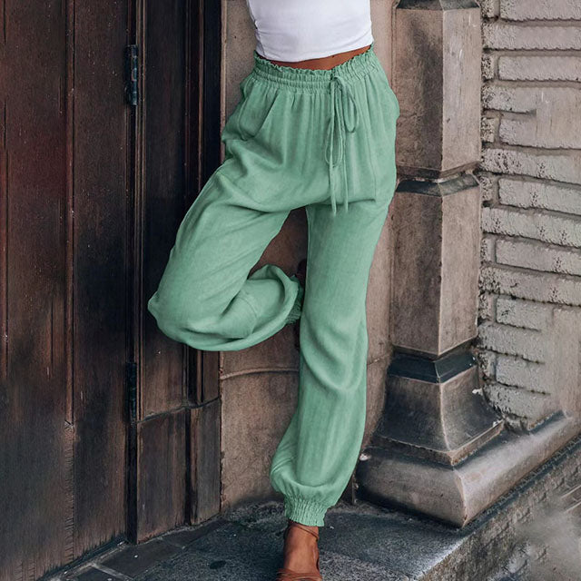 A woman in slim tapered drawstring joggers styled with sandals for an elegant, relaxed look.