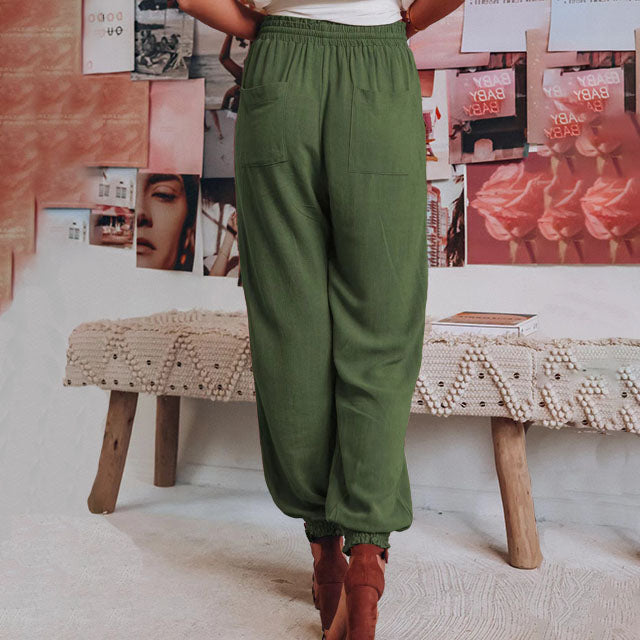 A woman in slim tapered drawstring joggers styled with sandals for an elegant, relaxed look.