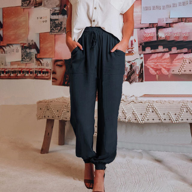 A woman in slim tapered drawstring joggers styled with sandals for an elegant, relaxed look.