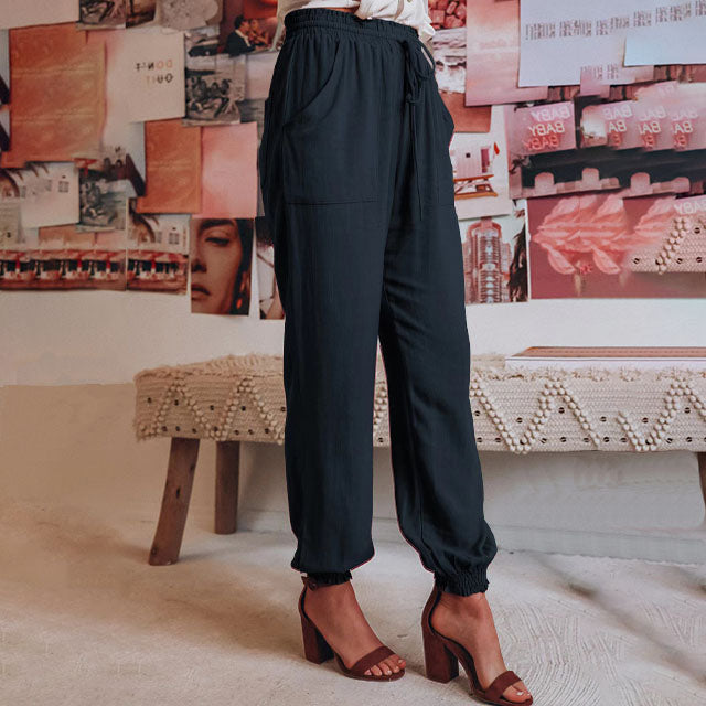 A woman in slim tapered drawstring joggers styled with sandals for an elegant, relaxed look.