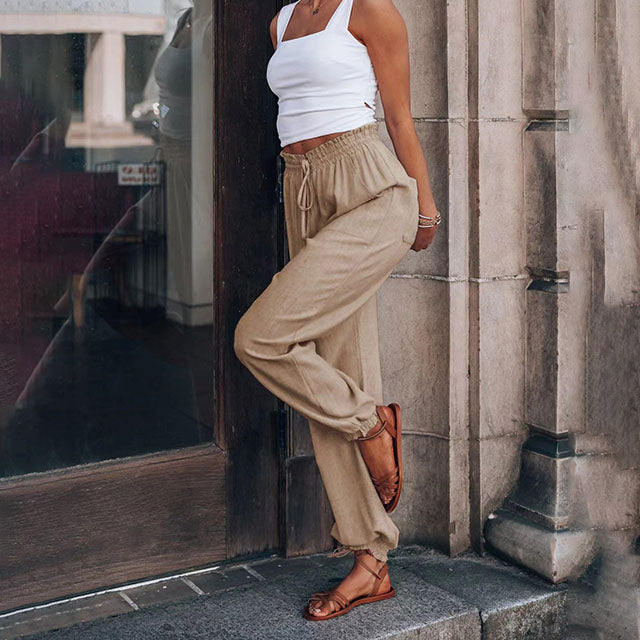 A woman in slim tapered drawstring joggers styled with sandals for an elegant, relaxed look.