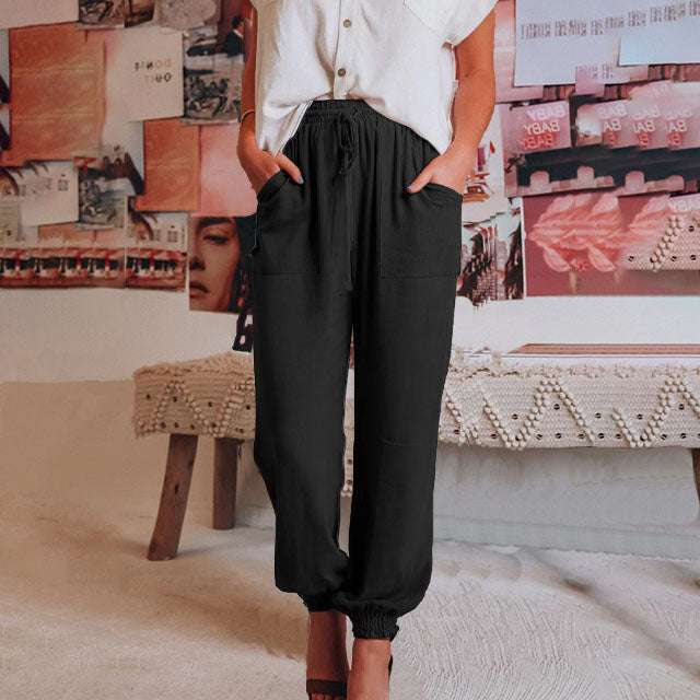 A woman in slim tapered drawstring joggers styled with sandals for an elegant, relaxed look.