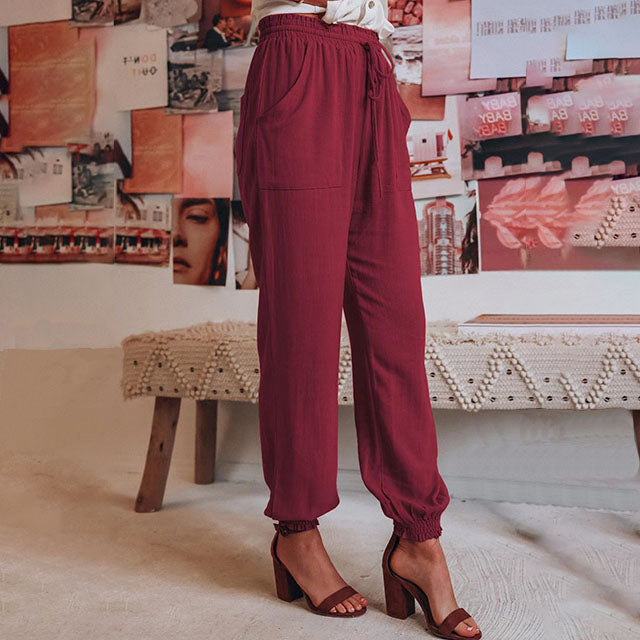 A woman in slim tapered drawstring joggers styled with sandals for an elegant, relaxed look.