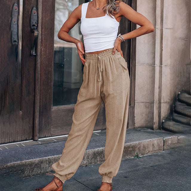 A woman in slim tapered drawstring joggers styled with sandals for an elegant, relaxed look.