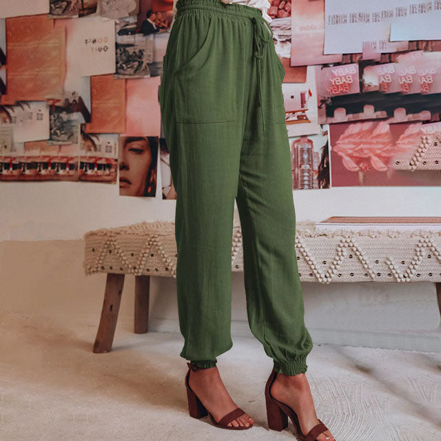 A woman in slim tapered drawstring joggers styled with sandals for an elegant, relaxed look.