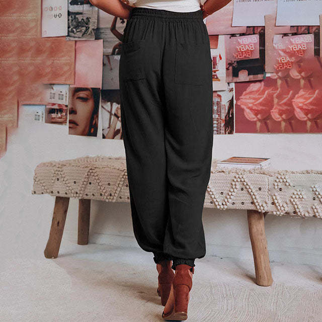 A woman in slim tapered drawstring joggers styled with sandals for an elegant, relaxed look.