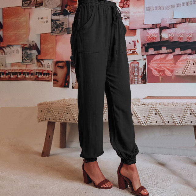 A woman in slim tapered drawstring joggers styled with sandals for an elegant, relaxed look.