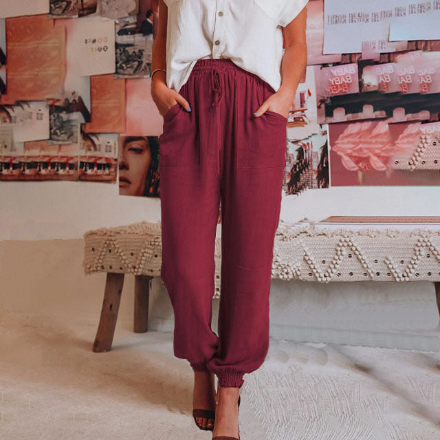 A woman in slim tapered drawstring joggers styled with sandals for an elegant, relaxed look.