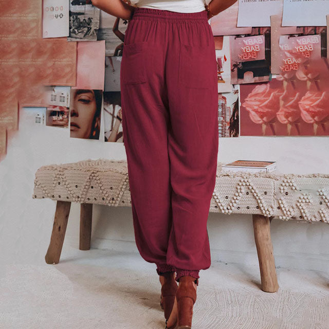 A woman in slim tapered drawstring joggers styled with sandals for an elegant, relaxed look.