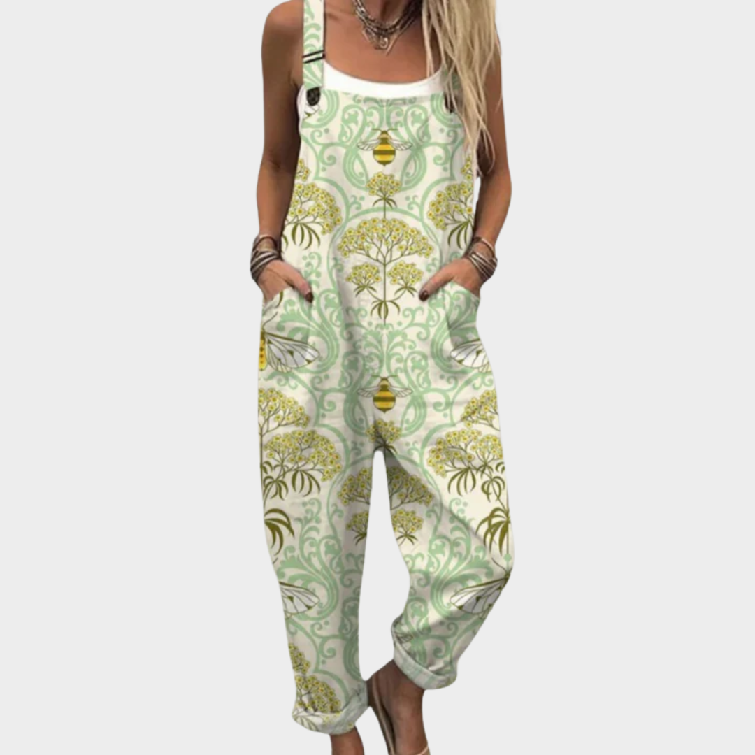 Woman wearing cream dungarees printed with golden blossoms, soft sage scrolls and little bees