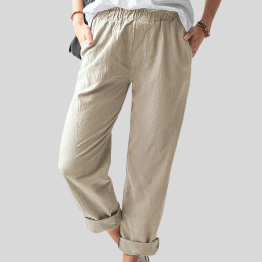 A woman standing relaxed in soft straight-leg trousers with a clean, elegant everyday look.