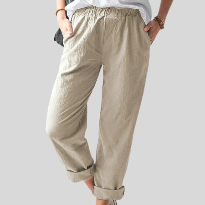 A woman standing relaxed in soft straight-leg trousers with a clean, elegant everyday look.