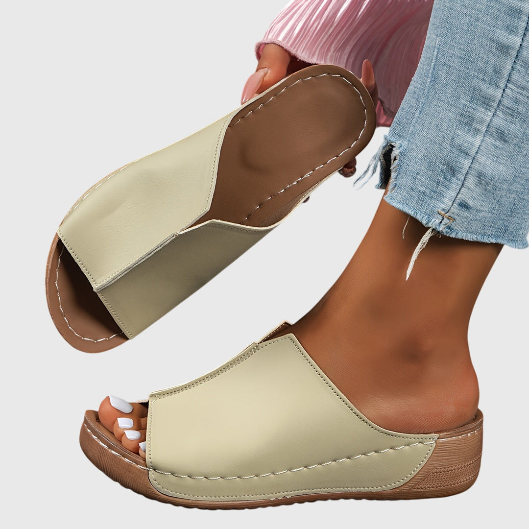 A woman wearing black platform slides on a relaxed day out.