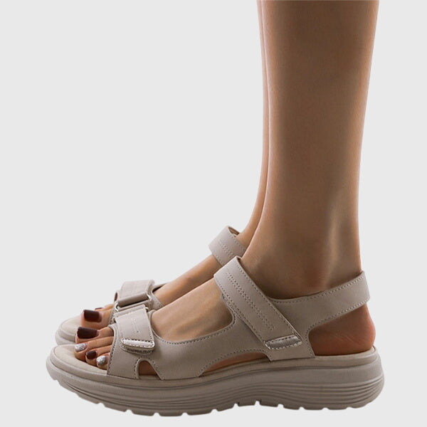 A woman in beige adjustable strap sandals standing steady and relaxed on a sunny path.